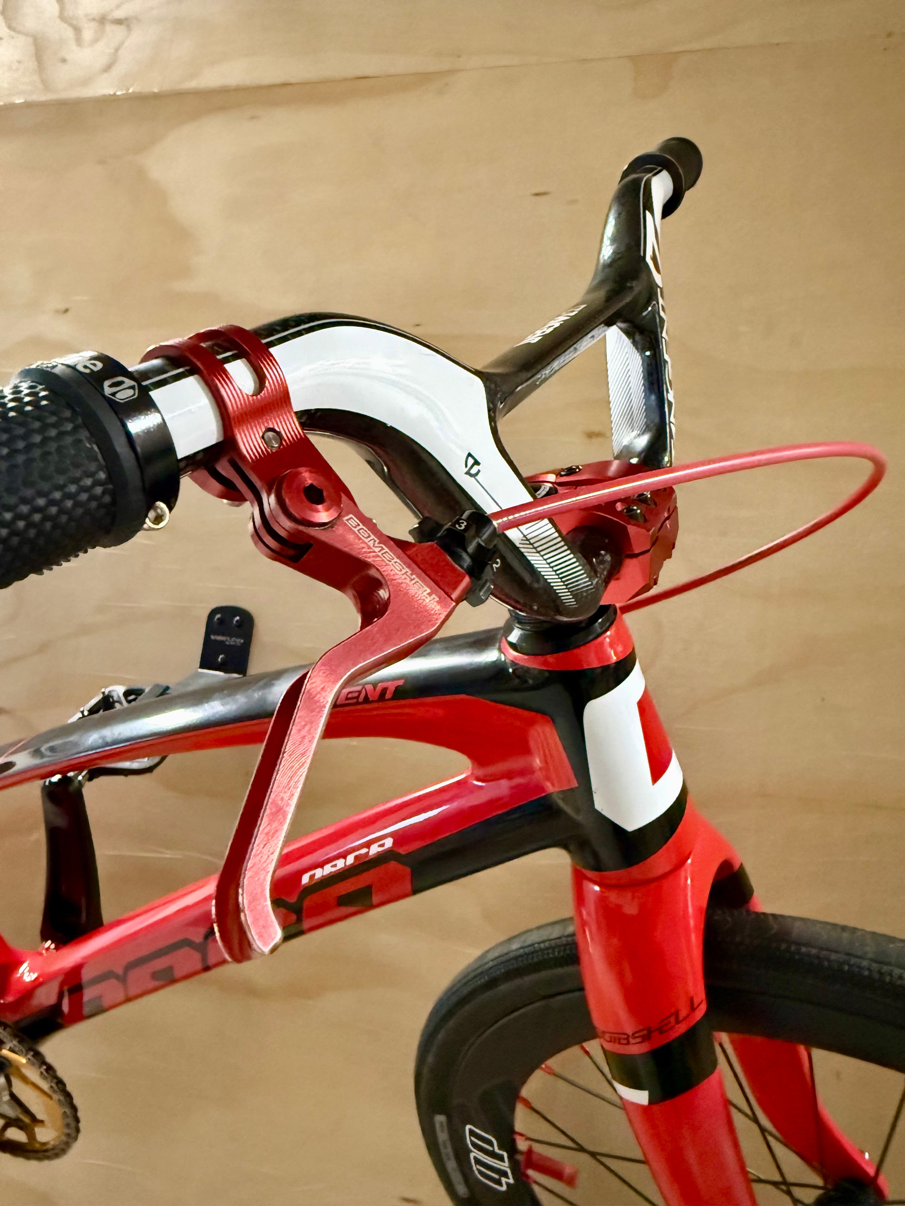 Close-up of a red bicycle handlebar with brake levers on a beige background