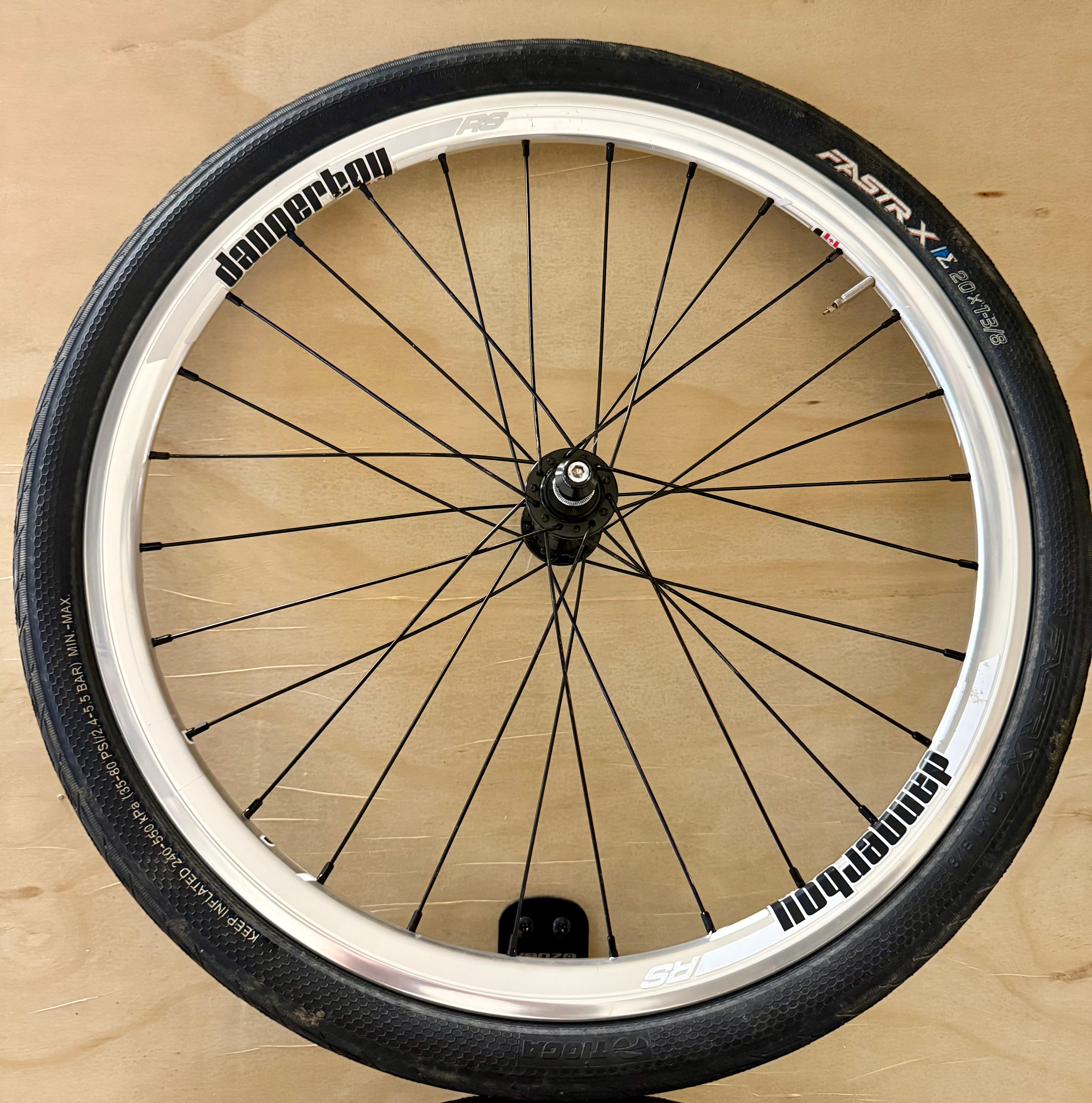 Bicycle wheel with black tires and white walls on a wooden surface
