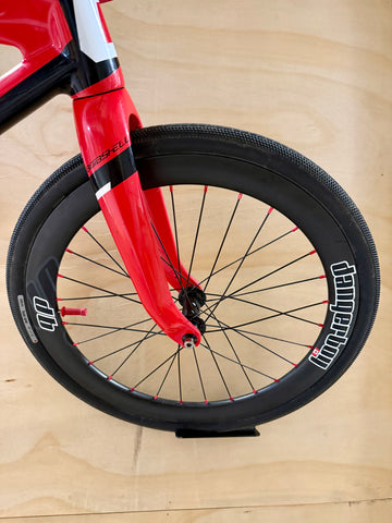Close-up of a red bicycle fork and black wheel on a wooden surface