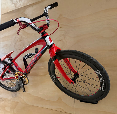 Red bicycle leaning against a wooden wall