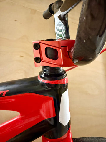 Close-up of a bicycle's head tube with red and black frame on a wooden background